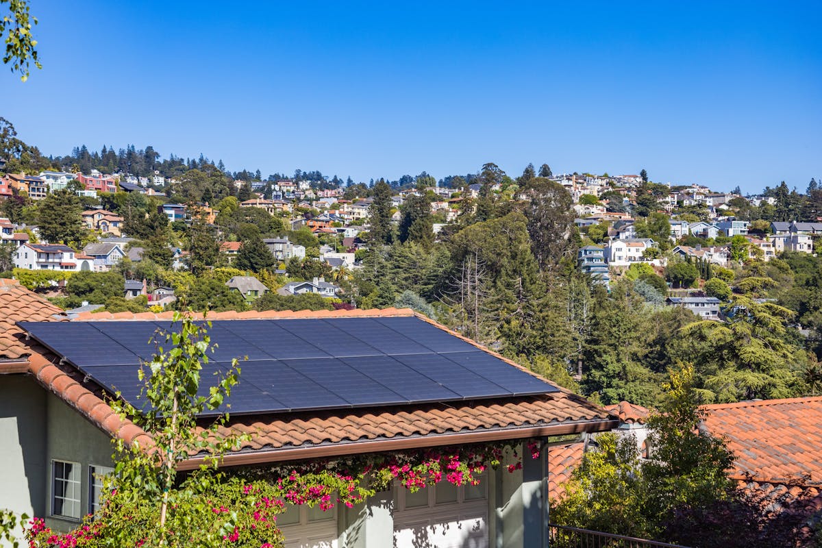 Residential solar panels on tile roof in a lush green Hawaii neighborhood