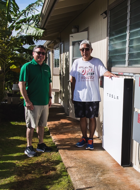 Happy customer with AEI team member next to Tesla Powerwall